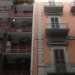 Foto 10. Siamo ora in via Davanzati, dove ci ritroviamo davanti a un altro condominio kitsch creato con mattonelle scure e ringhiere dei balconi rosse, costellato da numerosi condizionatori, adiacente a un grazioso edificio antico color salmone con raffinati timpani arrotondati 